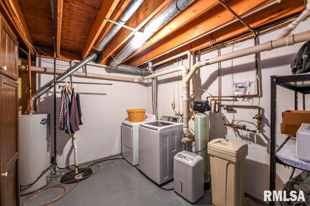 clothes washing area featuring laundry area, concrete block wall, washing machine and dryer, and water heater