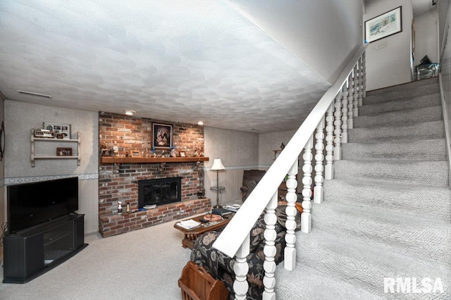 stairs with a fireplace, carpet, visible vents, and a textured ceiling