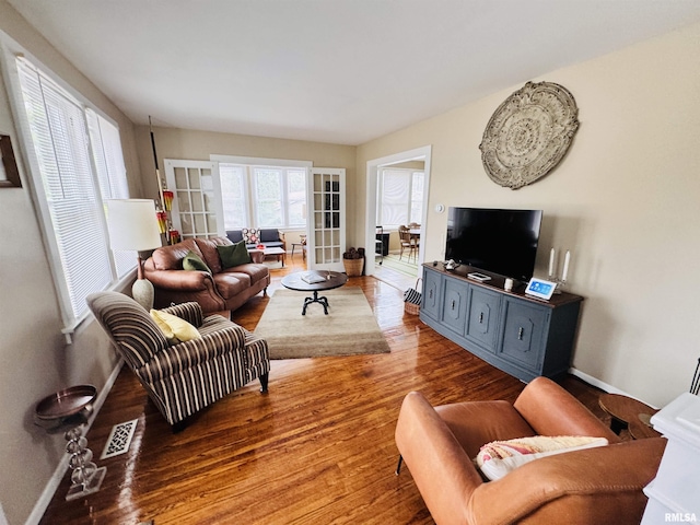 living room featuring visible vents, baseboards, and wood finished floors