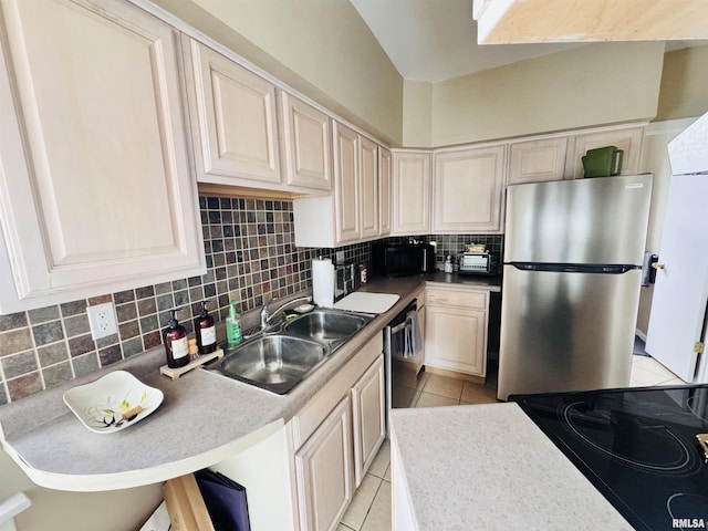 kitchen featuring backsplash, light countertops, light tile patterned floors, black appliances, and a sink