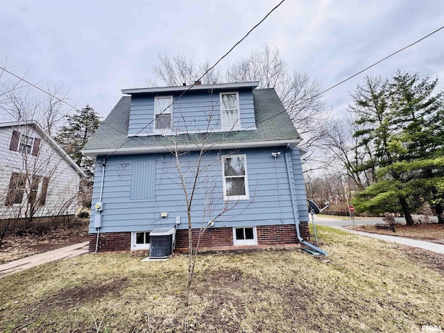 back of property featuring a lawn, cooling unit, and a shingled roof