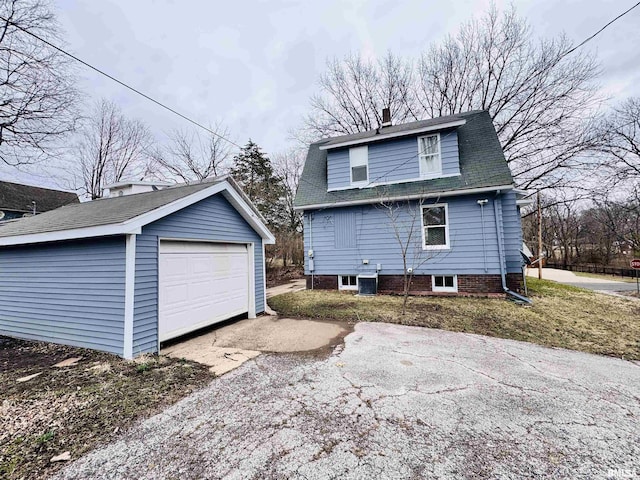 view of property exterior with aphalt driveway, a detached garage, an outdoor structure, and a chimney