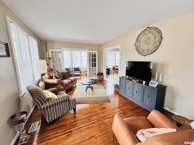 living room with plenty of natural light, wood finished floors, visible vents, and baseboards