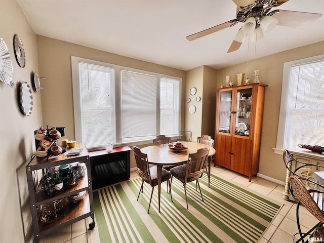 dining space with light tile patterned floors, baseboards, and ceiling fan