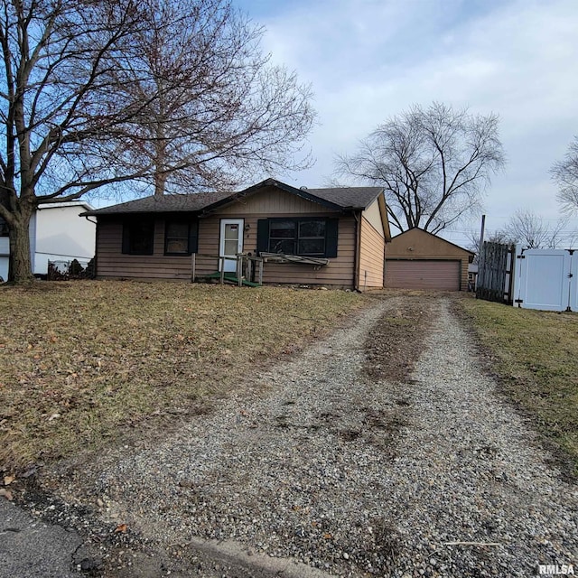 view of front of house with fence, a garage, an outbuilding, driveway, and a gate