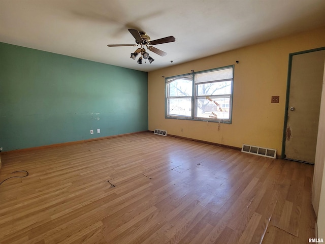 unfurnished room featuring visible vents, baseboards, wood finished floors, and a ceiling fan