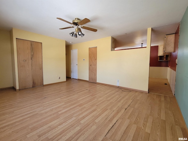 interior space featuring a ceiling fan, light wood-type flooring, and baseboards