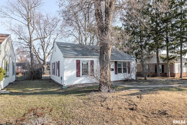 view of front facade featuring a front lawn, fence, and roof with shingles