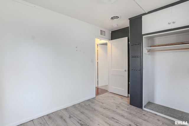 unfurnished bedroom with visible vents, baseboards, light wood-style floors, and a closet