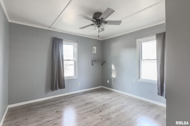 empty room featuring a ceiling fan, crown molding, wood finished floors, and baseboards