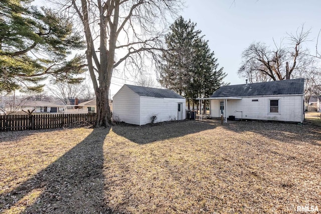 rear view of house with an outdoor structure and fence