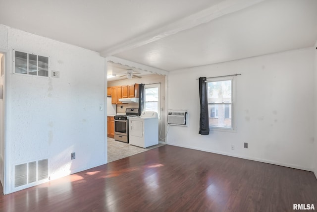 unfurnished living room with visible vents, beamed ceiling, an AC wall unit, light wood-type flooring, and washer / dryer