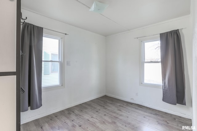 empty room featuring plenty of natural light, wood finished floors, and baseboards