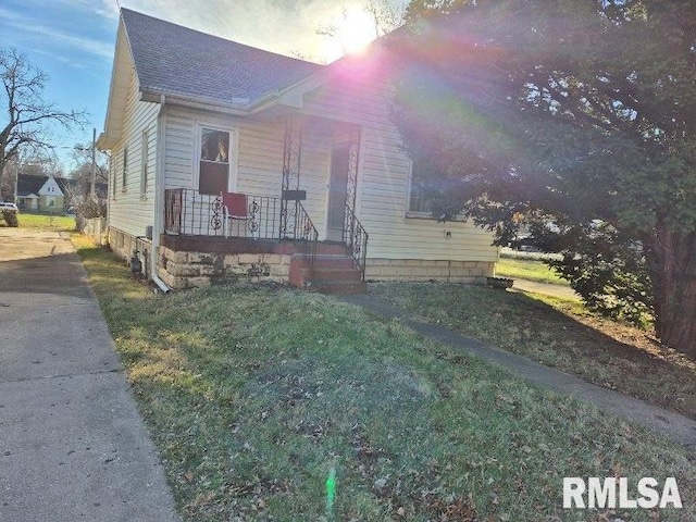 view of front facade with a porch, a front yard, and roof with shingles