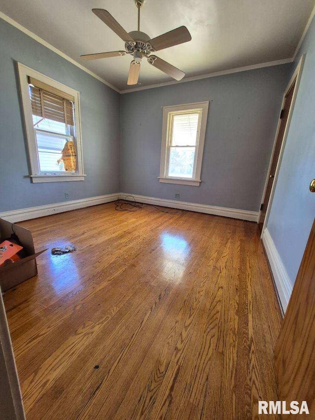 unfurnished bedroom featuring ceiling fan, wood finished floors, baseboards, and ornamental molding