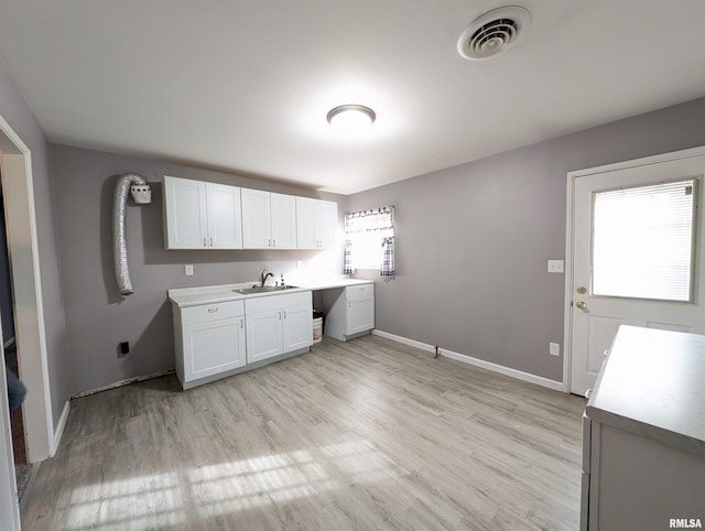 washroom with visible vents, light wood-type flooring, a sink, cabinet space, and baseboards