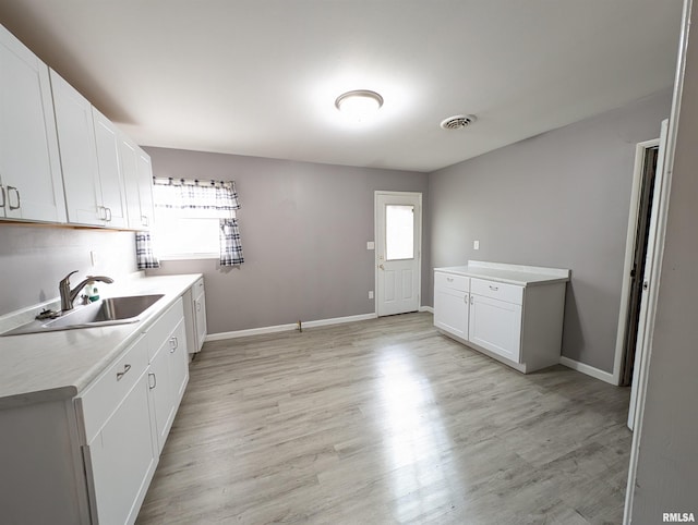 kitchen featuring plenty of natural light, light wood-type flooring, light countertops, and a sink