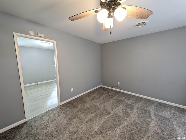 carpeted spare room with visible vents, baseboards, and ceiling fan