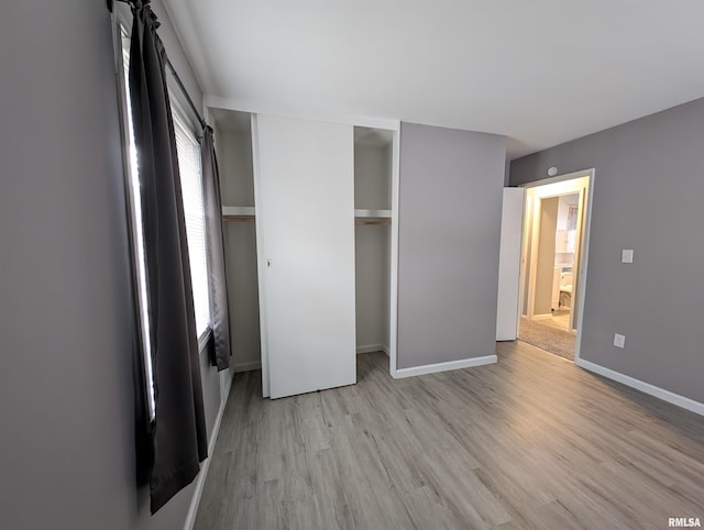 unfurnished bedroom featuring a closet, baseboards, and light wood finished floors