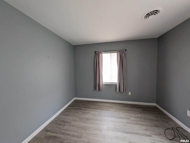 spare room with visible vents, baseboards, and wood finished floors