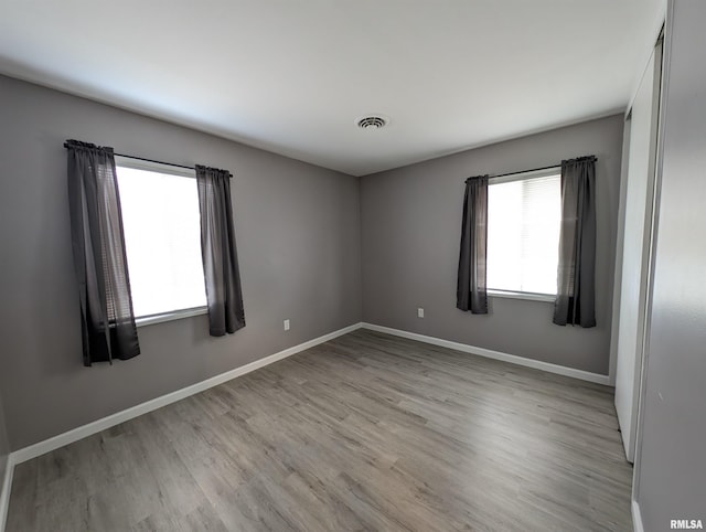 unfurnished room featuring light wood-style flooring, visible vents, and baseboards