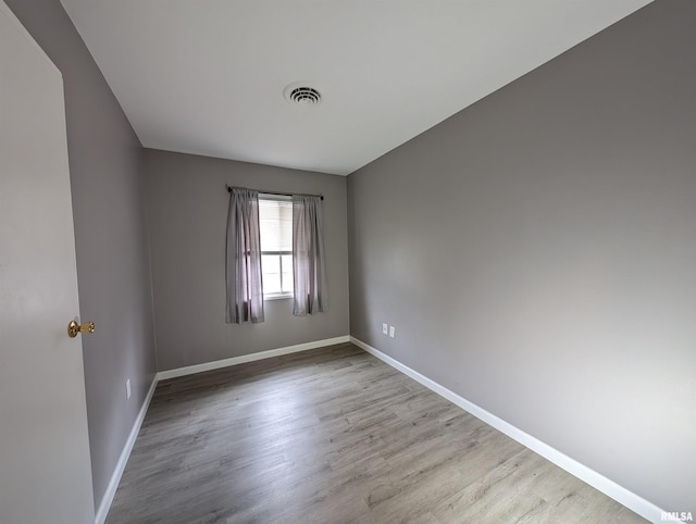 spare room with visible vents, baseboards, and wood finished floors