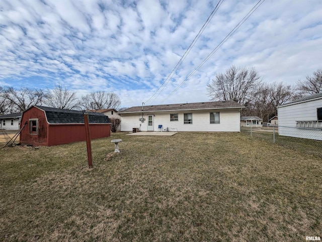 rear view of property featuring a yard, an outdoor structure, a patio, and fence