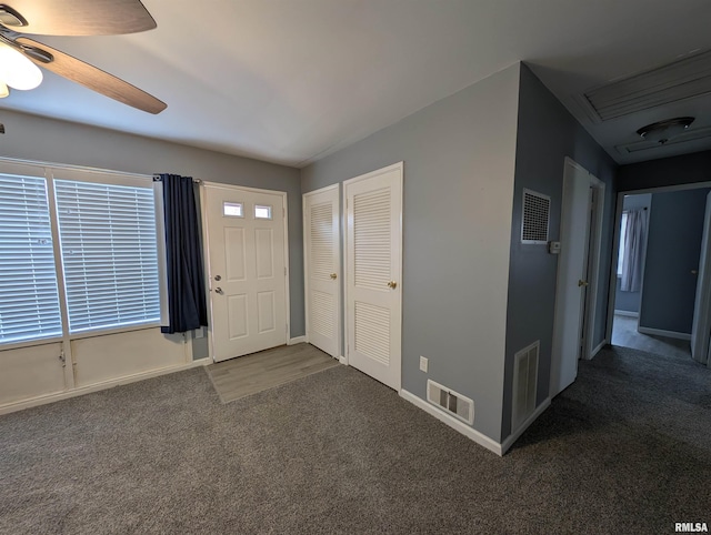 entryway with visible vents, carpet floors, and a ceiling fan