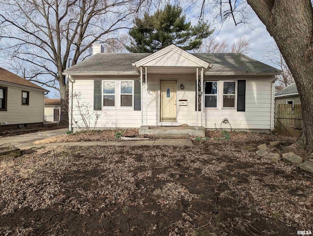 bungalow with a shingled roof, a chimney, and fence