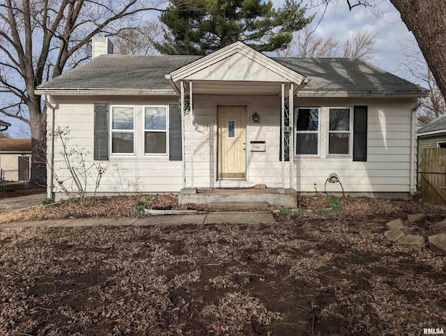 bungalow featuring a chimney, fence, and roof with shingles