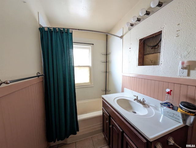 full bath with tile patterned floors, a wainscoted wall, vanity, and shower / bath combo with shower curtain