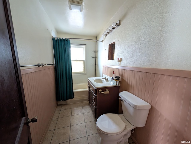 full bathroom with shower / bath combo with shower curtain, toilet, wainscoting, tile patterned floors, and vanity