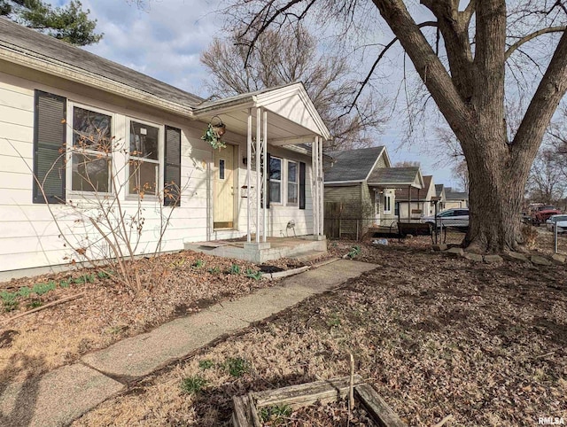 view of side of property with covered porch and fence