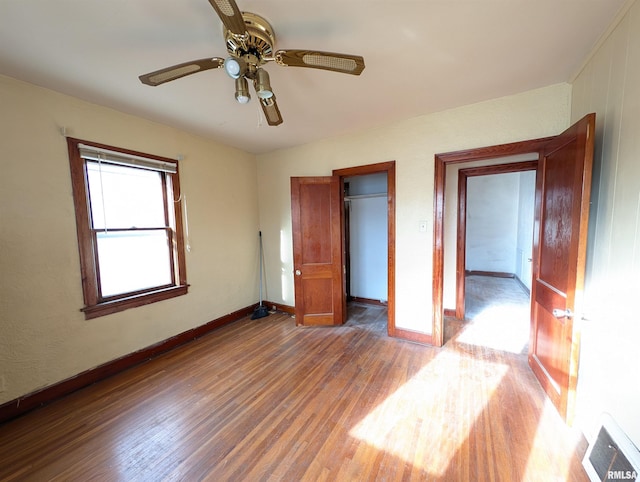 unfurnished bedroom with wood finished floors, visible vents, baseboards, ceiling fan, and a closet