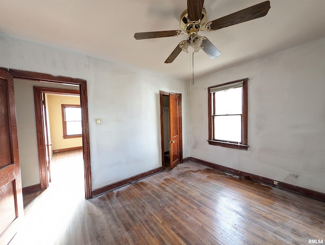 empty room featuring a ceiling fan, wood finished floors, and baseboards