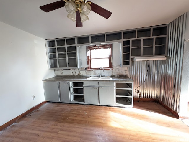 kitchen with a ceiling fan, open shelves, gray cabinetry, a sink, and light wood-style floors