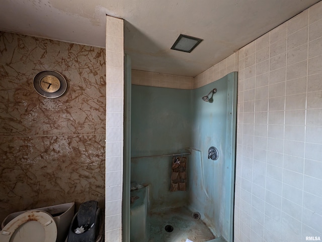 bathroom with a shower stall and tile walls