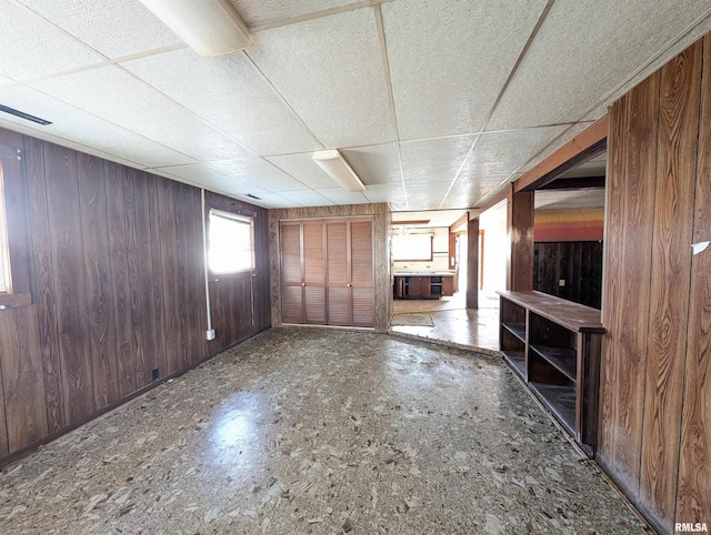 unfurnished living room with wooden walls and a paneled ceiling