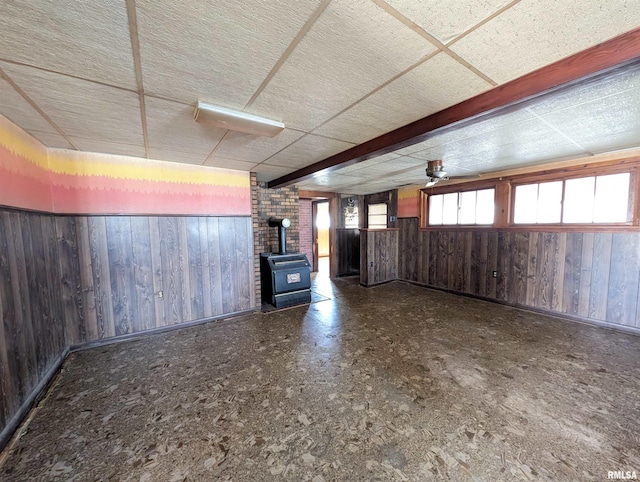 interior space featuring a wood stove, wooden walls, and a paneled ceiling