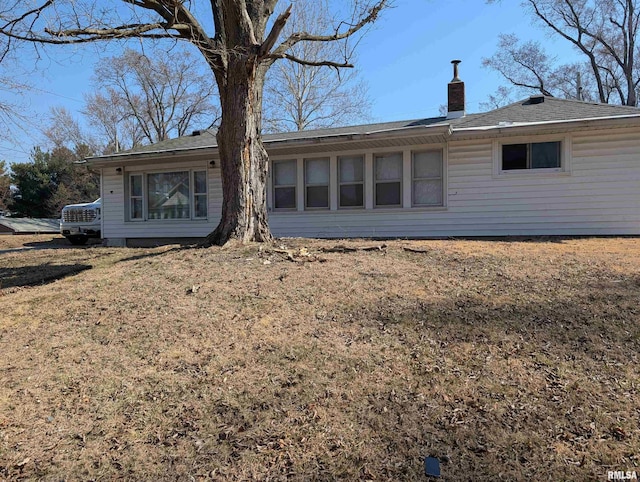 rear view of house with a yard and a chimney