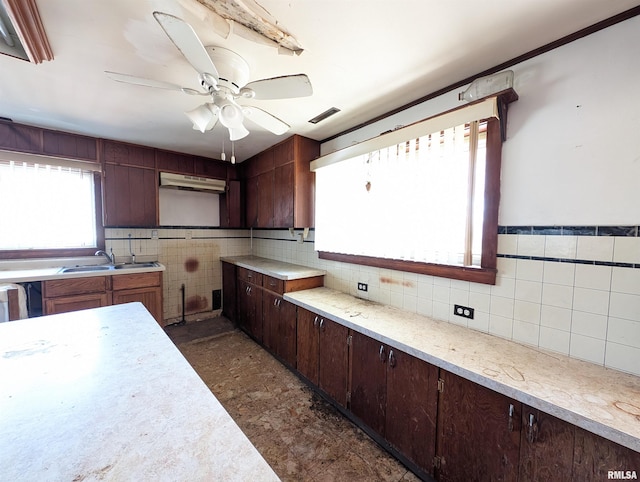 kitchen featuring light countertops, dark brown cabinets, a ceiling fan, and a sink