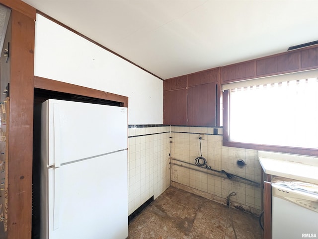 kitchen featuring tile walls and freestanding refrigerator