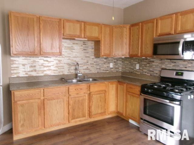 1209 S 4th St, Pekin, IL 61554 - kitchen with appliances with stainless steel finishes, tasteful backsplash, dark wood finished floors, and light brown cabinets