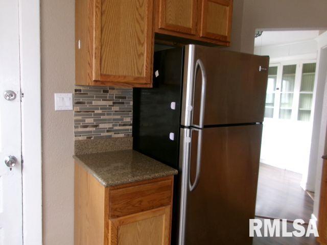 1209 S 4th St, Pekin, IL 61554 - kitchen with freestanding refrigerator, decorative backsplash, and stone countertops
