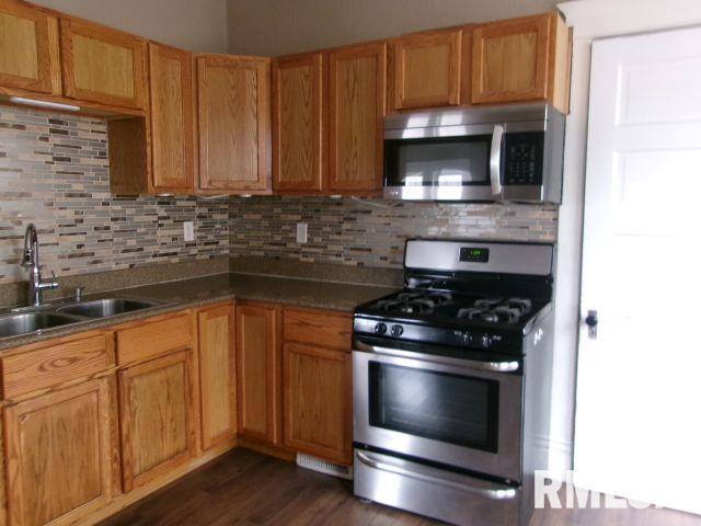 1209 S 4th St, Pekin, IL 61554 - kitchen with appliances with stainless steel finishes, backsplash, and dark wood-style floors