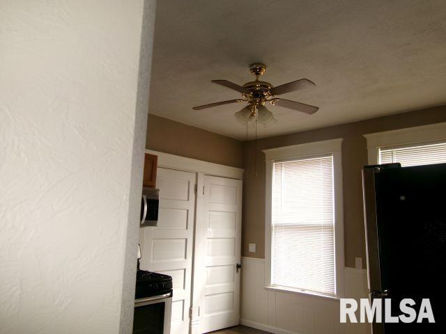 1209 S 4th St, Pekin, IL 61554 - kitchen featuring appliances with stainless steel finishes, ceiling fan, and a wainscoted wall