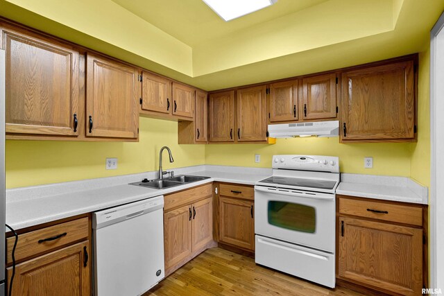 kitchen featuring light countertops, white appliances, under cabinet range hood, a sink, and light wood finished floors