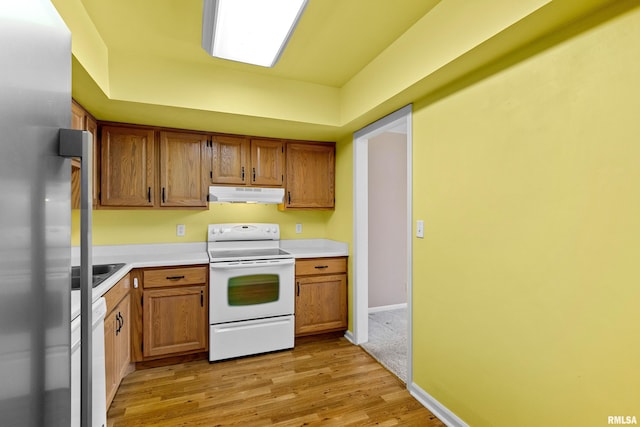 kitchen featuring under cabinet range hood, light countertops, light wood-style floors, and white appliances