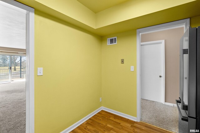 empty room with baseboards, visible vents, wood finished floors, and carpet floors