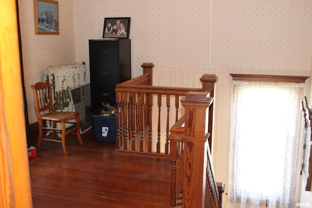 stairway with wallpapered walls and wood finished floors